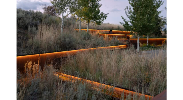 As night falls, lighting reveals a quiet composition of steel, sagebrush, and shadow. The runnel animates the space with sound and reflection—transforming the entry from a utilitarian zone into a sculptural and ecological moment.